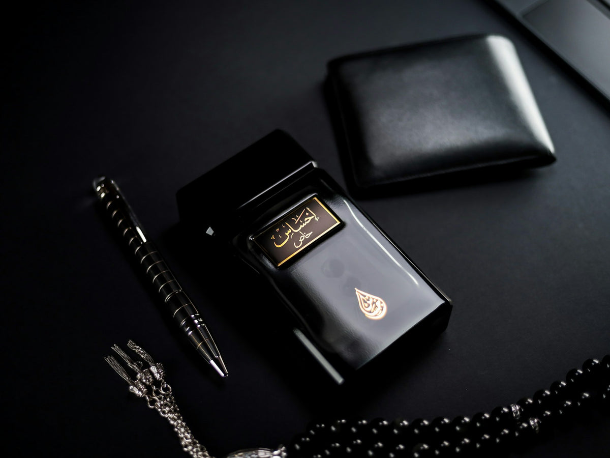 Rasasi perfumes — flat lay of an Arabian perfume bottle with pen, wallet and prayer beads