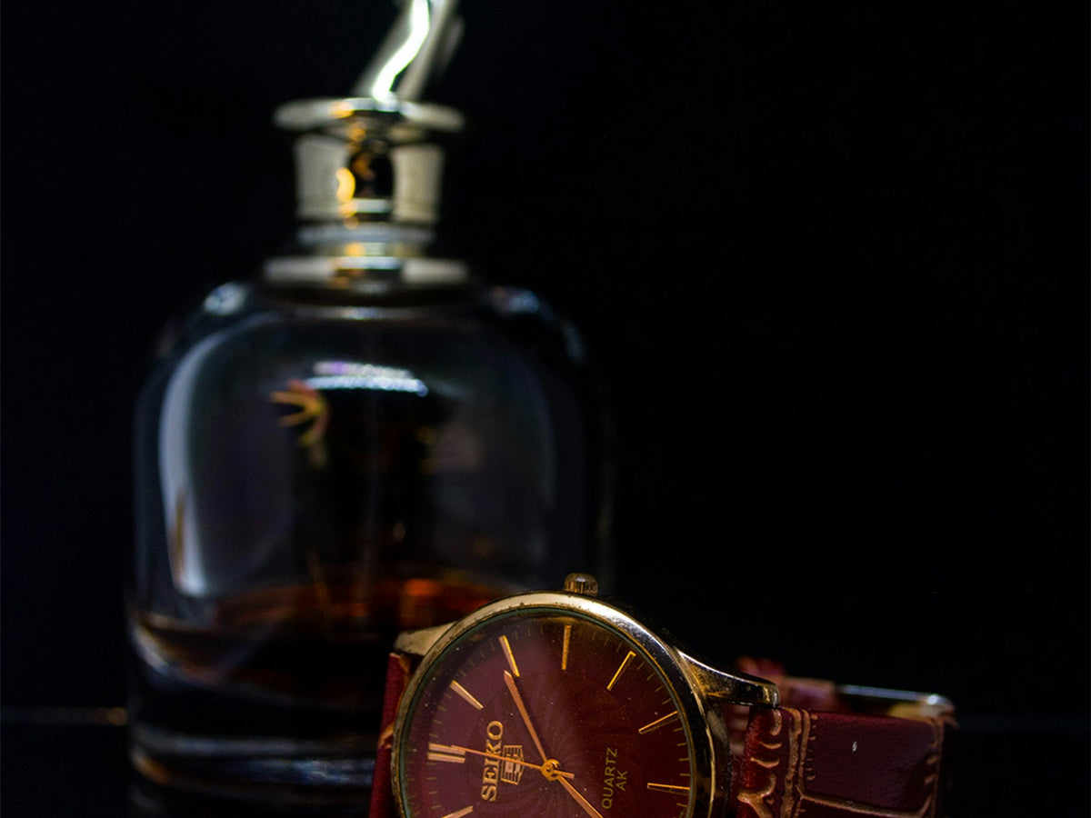 Armaf fragrances — amber glass cologne bottle with a wristwatch on a dark surface