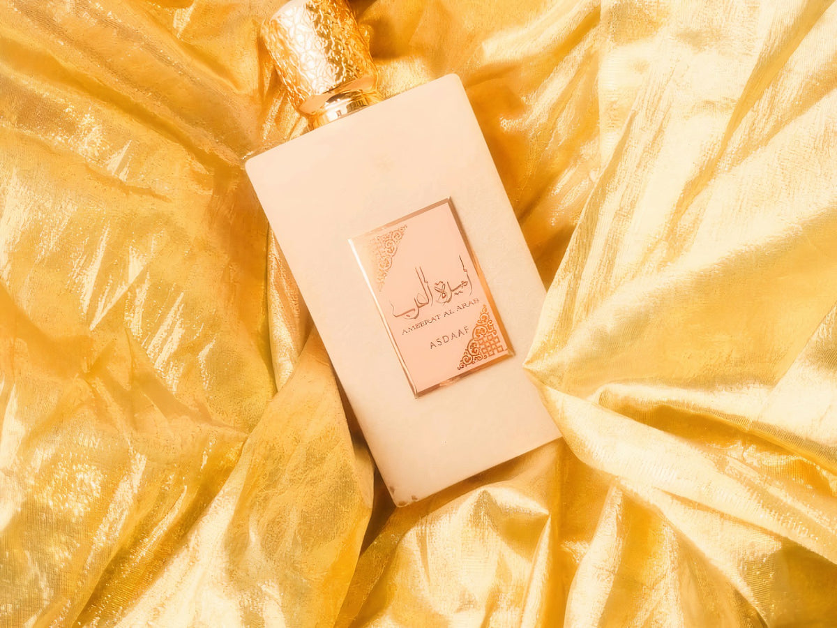 Maison Alhambra — blush pink eau de parfum bottle resting on gold silk